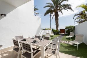 a dining table and chairs on a patio with palm trees at Villa in Parque Santiago III in Playa de las Americas
