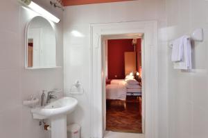 a bathroom with a sink and a mirror and a bedroom at Bed and Breakfast "Caffe-caffe" in Kikinda