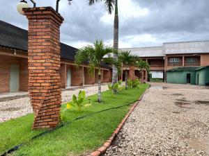 un pilar de ladrillo junto a un edificio con palmeras en Villa Green Hotel, en Tomé-Açu