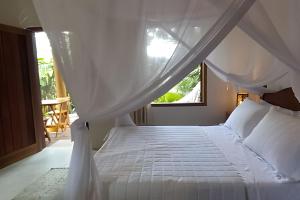 a bedroom with a white bed with a window at Licuri Praia de Algodões à poucos passos do mar. in Marau