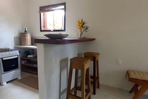 a kitchen with a counter with two stools at Licuri Praia de Algodões à poucos passos do mar. in Marau