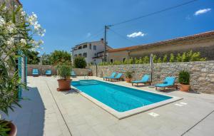 a swimming pool in a yard with chairs and a wall at Lovely Home In Selina in Selina
