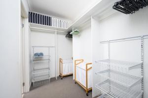 un dressing avec des murs blancs et des étagères blanches dans l'établissement Modern Family Friendly Retreat Home with Sunroom, à Clyde North