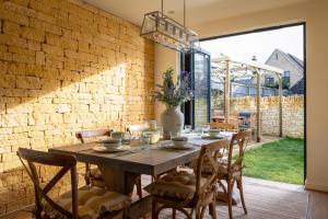 een eetkamer met een houten tafel en stoelen bij Broadway Country Chic Cottage in Broadway