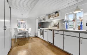 a kitchen with white cabinets and a table and chairs at 4 Bedroom Awesome Home In Grenaa in Grenå
