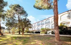 Un gran edificio blanco con árboles delante. en Nice Apartment In Argeles-Sur-Mer, en Argelès-sur-Mer
