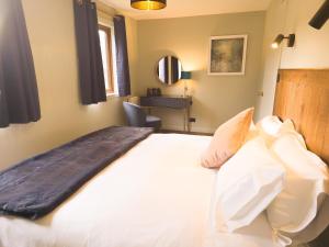 a bedroom with a large bed with white sheets and pillows at Fraser Cottage in Kincraig