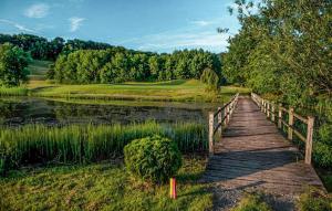 a wooden bridge over a pond next to a golf course at 1 Bedroom Awesome Apartment In Binowo in Binowo