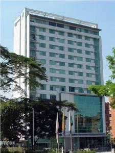 un edificio alto con banderas delante en Novelty Suites Hotel, en Medellín