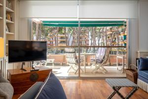 een woonkamer met een flatscreen-tv en stoelen bij AT103 Pins Beachfront complex, beach view in Torredembarra