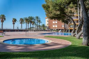 een zwembad in een park met palmbomen en een gebouw bij AT103 Pins Beachfront complex, beach view in Torredembarra