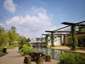 a garden with a pond and a pergola at Sea View Cozy 2BR Green Haven -Permas Masai CIQ -7 to 9pax in Masai
