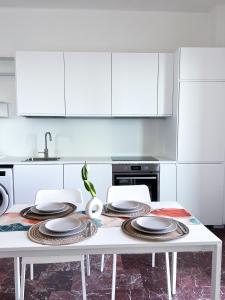 una cocina blanca con una mesa con platos. en Isabel apulian apartment, en Molfetta