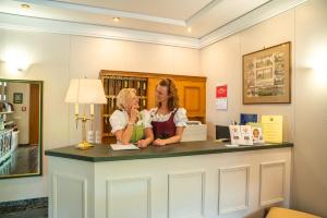 dwie kobiety stojące przy ladzie w bibliotece w obiekcie Hotel Haus Arenberg w mieście Salzburg