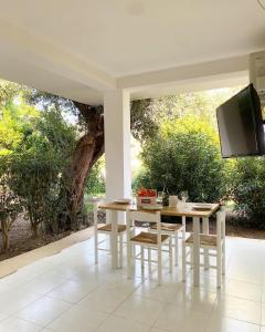 Una mesa blanca y sillas con un televisor en un patio. en Il Giardino Apartments - Peaceful atmosphere and free parking -, en Capo Vaticano
