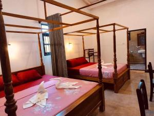 a bedroom with two beds and a table with a table sidx sidx sidx at Nautilus Cottage Unawatuna in Unawatuna
