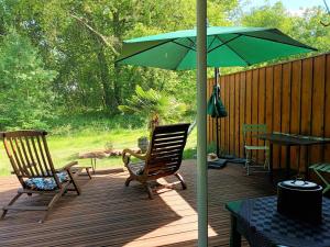 - une terrasse avec 2 chaises et un parasol vert dans l'établissement Gîte des Graves de Lilou, à Martillac