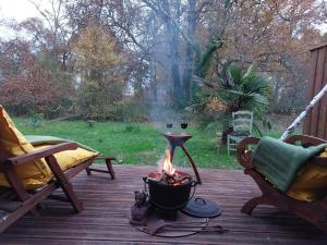 a fire pit on a wooden deck with a view of a yard at Gîte des Graves de Lilou in Martillac