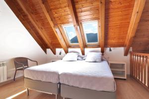 a bedroom with a bed and two windows at Aparthotel Nou Vielha in Vielha