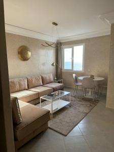 een woonkamer met een bank en een tafel bij Darkoum Apartment Anza in Agadir