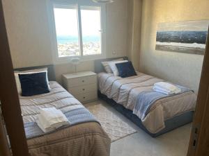 two beds in a room with two windows at Darkoum Apartment Anza in Agadir