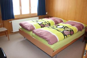 1 Schlafzimmer mit 2 Betten mit bunten Decken und Kissen in der Unterkunft Chalet Mittaghorn in Adelboden