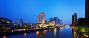 a river in a city at night with tall buildings at RIHGA Royal Hotel Osaka, Vignette Collection by IHG in Osaka