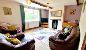 a living room with two leather couches and a fireplace at THE OLD WASH KITCHEN - Charming Character Cottage in Holmfirth, Yorkshire in Holmfirth