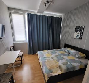 a bedroom with a bed and a desk and a window at Стаи за гости Пауза in Stara Zagora