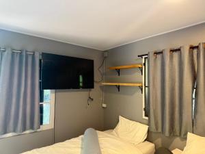 a bedroom with a bed and a tv on the wall at บ้านเชิงเขาโฮมสเตย์ บ้านบนเขา in Ban Mai