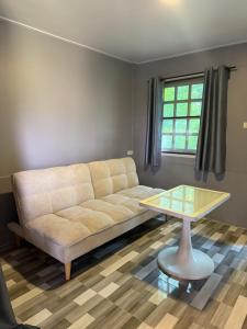 a living room with a couch and a table at บ้านเชิงเขาโฮมสเตย์ บ้านบนเขา in Ban Mai