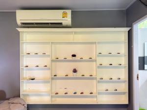 a white book shelf with vases on it at บ้านเชิงเขาโฮมสเตย์ บ้านบนเขา in Ban Mai