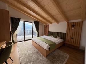 ein Schlafzimmer mit einem Bett und einem großen Fenster in der Unterkunft Liniștea Codrului in Borşa