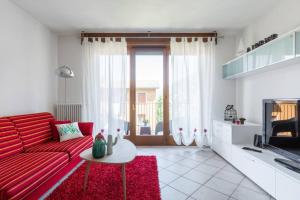 a living room with a red couch and a table at Modern apartment with balcony-garage-and pool in Bellano