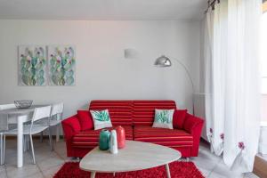 a red couch in a living room with a table at Modern apartment with balcony-garage-and pool in Bellano