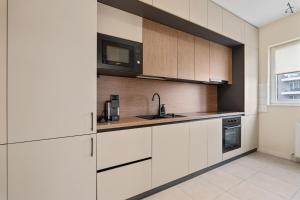 Una cocina con gabinetes blancos, un fregadero y un microondas. en Studio in Dimri Resident Ghencea, en Bucarest