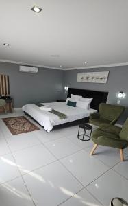 a bedroom with a large bed and two chairs at Grand Diamond Lodge in Roodepoort