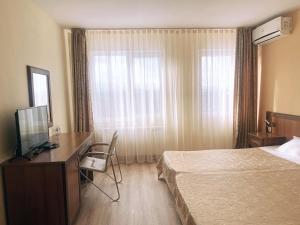 a hotel room with a bed and a desk and a television at Семеен хотел Балани in Gabrovo +17 photos