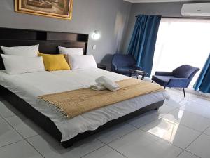 a bedroom with a large bed and two chairs at Grand Diamond Lodge in Roodepoort