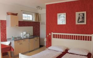 a bedroom with a red wall with a bed and a kitchen at Villa Mignon - Apartment Rot in Ostseebad Koserow