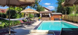 a swimming pool with chairs and umbrellas next to a house at Coquelicots Dordogne in Saint-Julien-de-Lampon