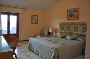 a bedroom with a bed and a chair and a window at Hotel L'Oasi in Cala Gonone