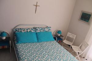 a bedroom with a bed with blue sheets and a cross on the wall at Casa Vacanze Mascali in Riposto
