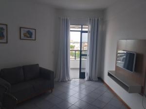 a living room with a couch and a television at flat no centro da Cidade in Campos dos Goytacazes