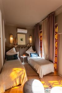 two beds sitting in a room with windows at Riad 117 in Marrakech
