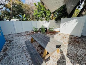 a wooden picnic table in a backyard with a fence at Blue Jay Bungalow - Cozy Oasis with Fire Pit in Dunedin +10 photos