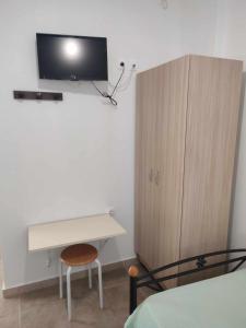 a bedroom with a desk and a cabinet with a tv on the wall at Filina's Room 1 in Maltezana