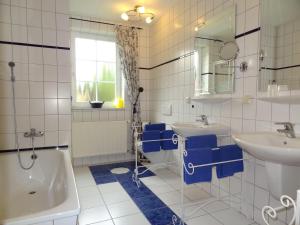 une salle de bain avec deux lavabos, une baignoire et un miroir dans l'établissement Ferienhof-Wohler-Wohnung-5, à Bojendorf 20 autres photos