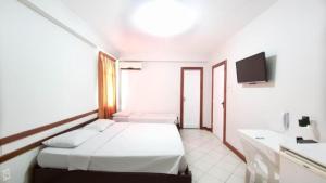 a white room with a bed and a tv at Pousada Central in Feira de Santana