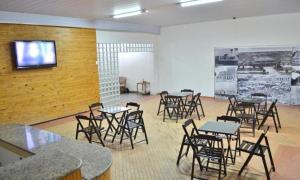 a room with tables and chairs and a tv on a wall at Pousada Central in Feira de Santana